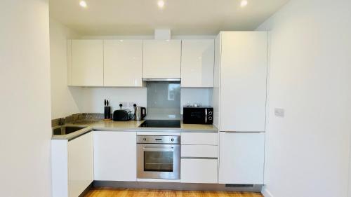a white kitchen with white cabinets and appliances at Urban Gem Apartment- Free parking in Enfield