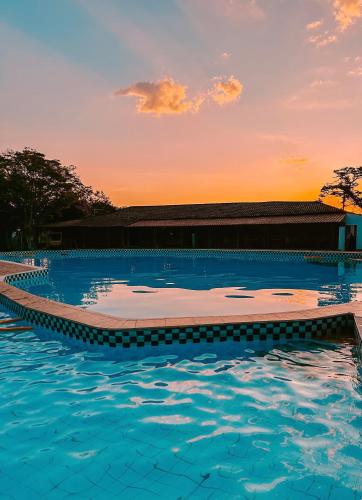 a swimming pool with a sunset in the background at Hotel Pontal de Tiradentes in Tiradentes