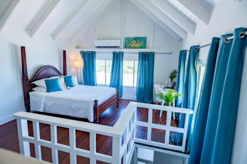 a bedroom with blue curtains and a bed in a room at Bay House Grenada in Belmont