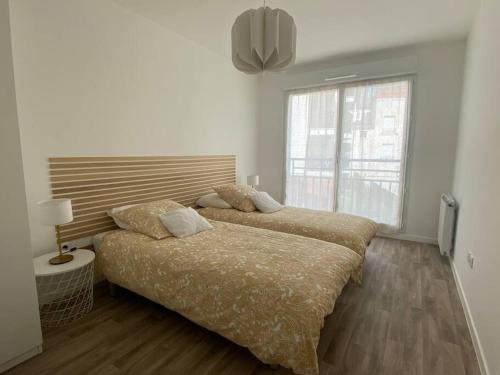 twee bedden in een witte kamer met een raam bij Fantastique 2 pièces à Créteil in Créteil