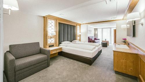 Habitación de hotel con cama y silla en Gourmet & Wine Hotel Austria - 4 Sterne superior, en Obergurgl