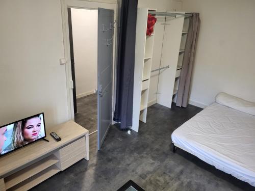 een slaapkamer met een tv en een bed en een spiegel bij APPARTEMENT Duo in Port-la-Nouvelle