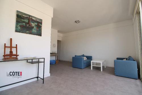 a living room with two blue chairs and a table at Le Briand in Carry-le-Rouet