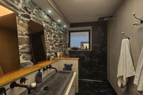 La salle de bains est pourvue d'un mur en pierre et d'un lavabo. dans l'établissement Exceptional stone mountain house, à Saint-Michel-de-Maurienne