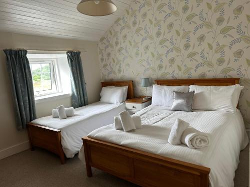 2 Einzelbetten in einem Schlafzimmer mit Fenster in der Unterkunft The Strontian Hotel in Strontian