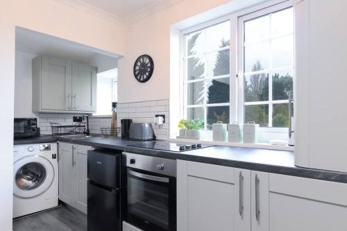 una cocina con armarios blancos y un reloj en la pared en Blissful 1 bed flat Bedworth, en Bedworth