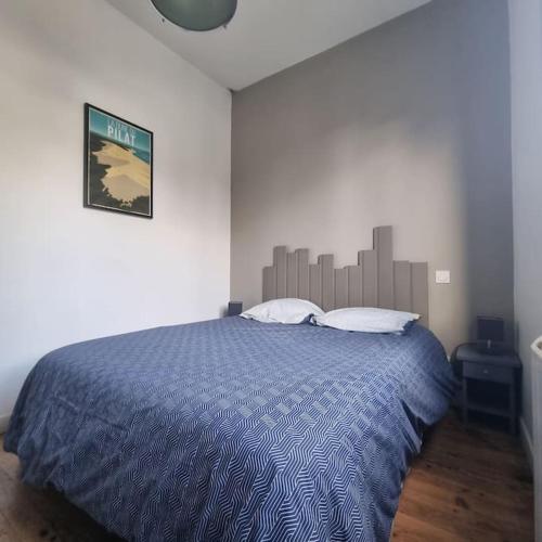 une chambre avec un grand lit avec une couette bleue dans l'établissement La cabane du Betey - Maison typique du bassin 150 m de la plage, à Andernos-les-Bains