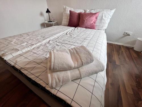 Una cama con almohadas rosas y una manta. en Zimmer in gepflegter Wohnung - in der Nähe des Bahnhofs - 3, en Paderborn