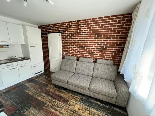 a living room with a couch against a brick wall at Engstliz Apartman in Foeni