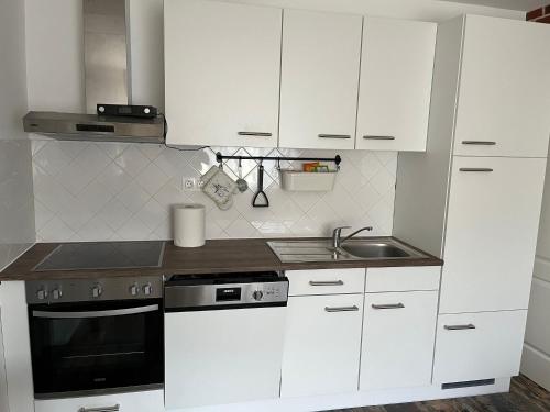 a kitchen with white cabinets and a stove and a sink at Engstliz Apartman in Foeni