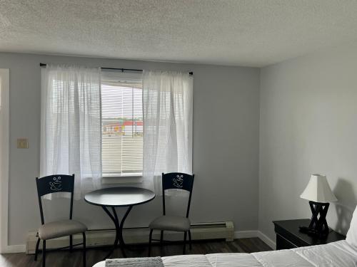 a bedroom with a table and two chairs and a window at Lincoln House Motel in Lincoln