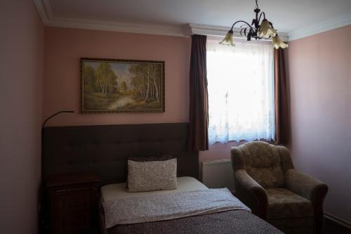 a bedroom with a bed and a chair and a window at Penzión ROYAL in Bytča