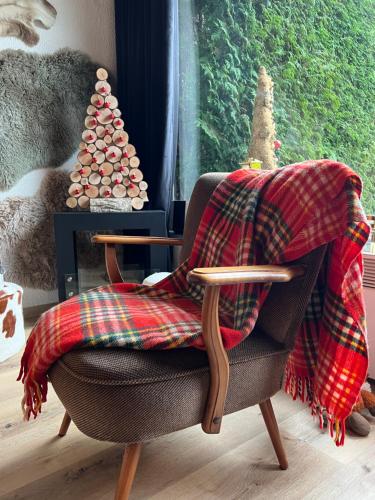 a blanket on a chair with a christmas tree at Cabane La Folie Douce in Hotton