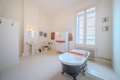 La salle de bains blanche est pourvue d'une baignoire et d'un lavabo. dans l'établissement Le Manoir du Belvédère - Piscine/Baby-Foot/Billard, à Castries
