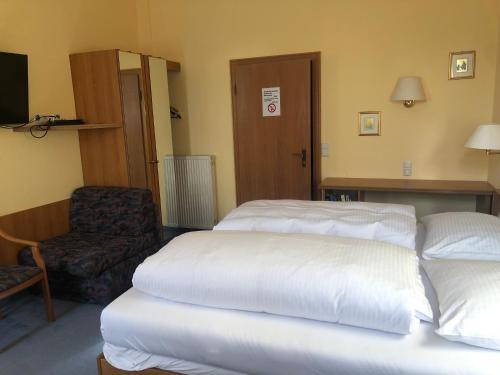 a hotel room with two beds and a chair at Gasthaus Klosterhof in Bronnbach
