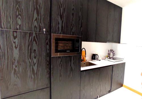 a kitchen with wooden cabinets and a microwave at Apart Hotel Banovani in Tbilisi City