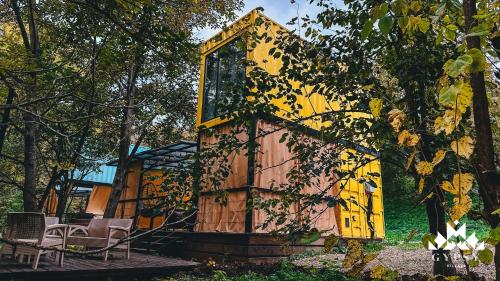 a small house with a yellow door and chairs at Gipsy Village Park Hotel in Asuretʼi
