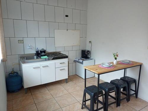 a kitchen with a table and stools and a sink at Apto confortável com Churrasqueira 02 in Cachoeira do Sul