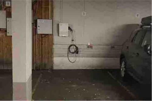 a car parked in a garage with a hose on the wall at Moderne leilighet med terrasse & gratis parkering in Kolbotn