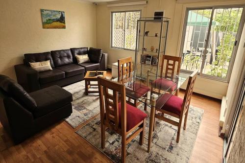 uma sala de estar com um sofá, uma mesa e cadeiras em Casa muy bien ubicada cercana al metro y a mall em Santiago
