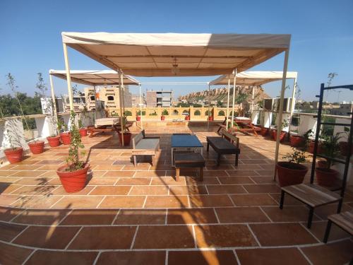 eine Terrasse mit Bänken und Tischen auf dem Dach in der Unterkunft Kiran Apartment in Jaisalmer