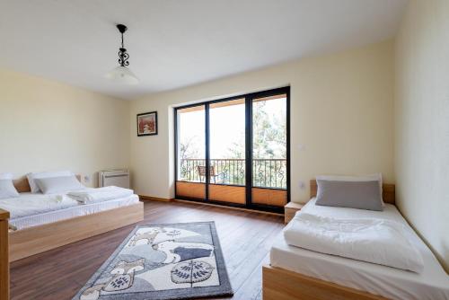a bedroom with two beds and a large window at ВИЛА МАРИНОВИ in Boykovo