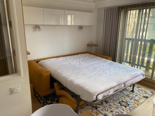 une petite pièce avec un lit et une fenêtre dans l'établissement DEAUVILLE CHARMANT STUDIO VUE MER résidence en travaux, à Deauville