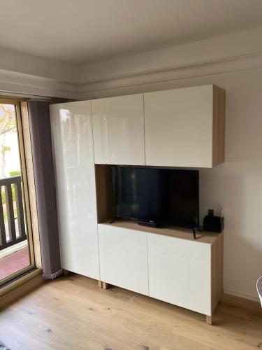 un salon avec une télévision et un meuble blanc dans l'établissement DEAUVILLE CHARMANT STUDIO VUE MER résidence en travaux, à Deauville