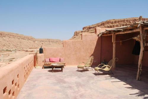 un patio con sillas y un sofá en el desierto en Kasbah Tigmi El Janoub, en Aït Ben Haddou