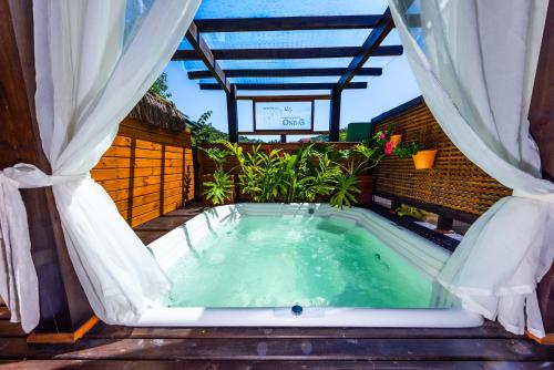 a jacuzzi tub on a patio with curtains at Residencial Caminho das Ondas in Bombinhas