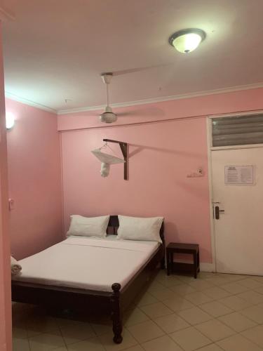 a bed in a room with a pink wall at Kibodya Hotel Nkrumah in Dar es Salaam