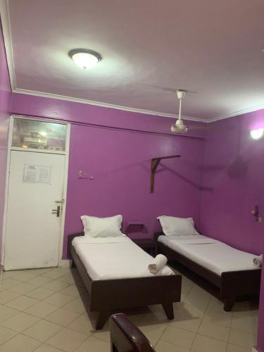 two beds in a room with purple walls at Kibodya Hotel Nkrumah in Dar es Salaam