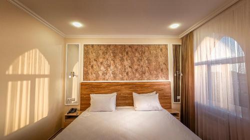 a bedroom with a large white bed with a window at Hotel Bankir Khiva in Khiva