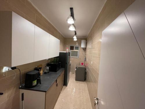 een keuken met witte kasten en een koelkast bij 4S private room in a shared appartment in Caïro