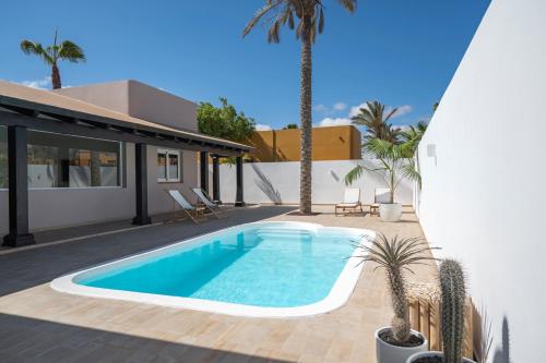 a swimming pool in the backyard of a house with palm trees at Villa Tropico - Design house with pool in Corralejo in Corralejo