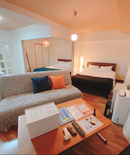 a living room with a couch and a bed at 札幌駅近 すすきの中心部 スーペリアルーム最大7名 家族やグループにお勧め 市電駅前 北海道観光食事最高立地 11歳まで子供無料 高級ベッドマットレス使用 チェックアウト11時 in Sapporo