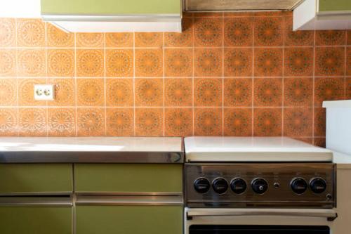a kitchen with a stove and a tile wall at Chez Christ in Noisy-le-Grand