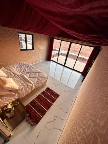a bedroom with a bed and two windows at Wadi Rum Golden Valley in Wadi Rum
