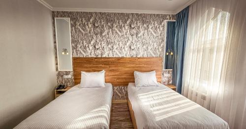 two beds in a small room with two windows at Hotel Bankir Khiva in Khiva
