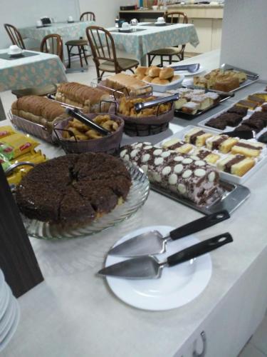 einen Tisch mit vielen verschiedenen Arten von Kuchen und Gebäck in der Unterkunft Hotel Boa Vista in Chapecó