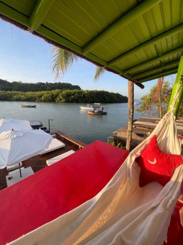 a hammock on a boat on a body of water at Casa Downtown in Caraíva