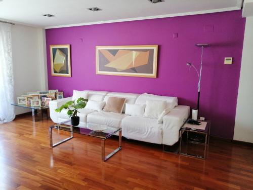 a living room with a white couch and a purple wall at Habitaciones doble in Almussafes