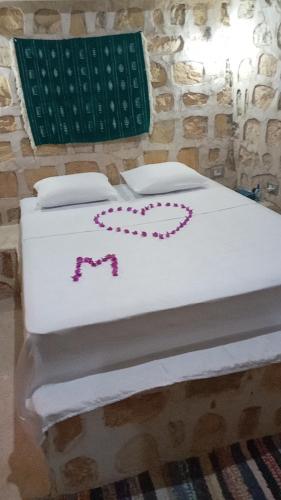 a white bed with pink decorations on it at Dar Fatma Toujane in Tūjān