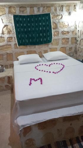 a white bed with pink decorations on it at Dar Fatma Toujane in Tūjān