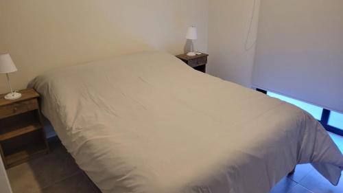 a white bed in a room with two night stands at Depto Edificio Vias Gualeguaychú, excelente in Gualeguaychú