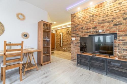 a living room with a television and a brick wall at Apartament Centrum III in Bydgoszcz
