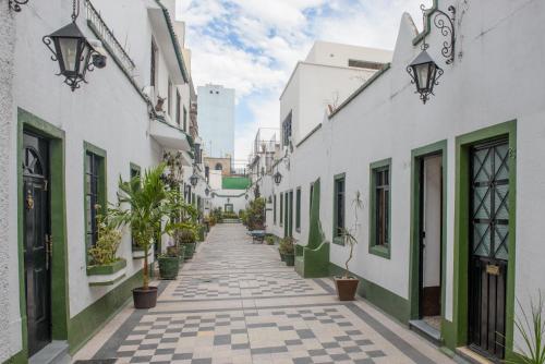 an alley with white buildings and potted plants at Charming House at Roma in Mexico City