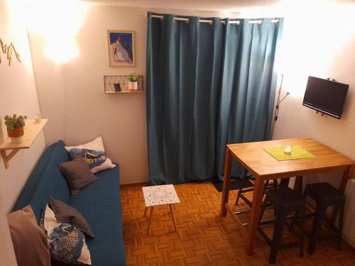 un salon avec un canapé bleu et une table dans l'établissement Rez de jardin / pieds des pistes, à Bernex