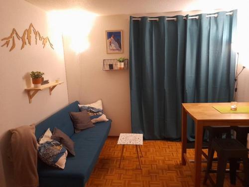 un salon avec un canapé bleu et une table dans l'établissement Rez de jardin / pieds des pistes, à Bernex