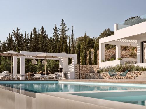 a pool with chairs and umbrellas next to a building at Meraki in Agios Nikolaos